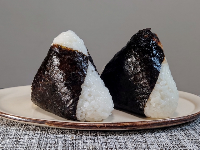 Two simple Japanese onigiri wrapped with nori, illustrating one of the most familiar ways to enjoy freshly cooked rice.