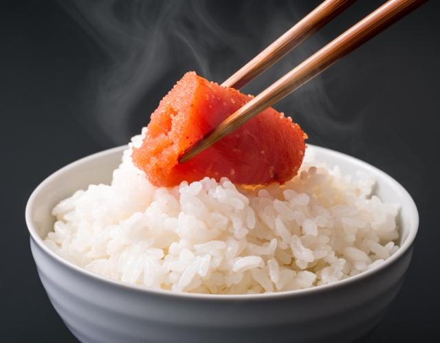 A bowl of steamed Japanese rice topped with a piece of mentaiko, a common rice companion known as gohan no tomo.