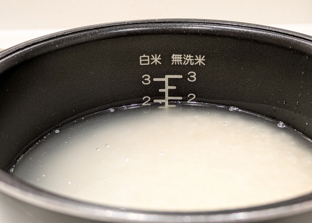 Uncooked Japanese rice soaking in water inside a rice cooker