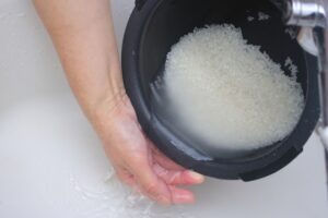 Rinsing Japanese rice gently under running water before cooking.