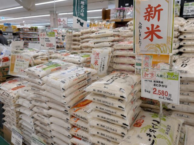 A Japanese supermarket rice aisle displaying bags of newly harvested rice with prominent “Shinmai” signs and seasonal promotional displays.