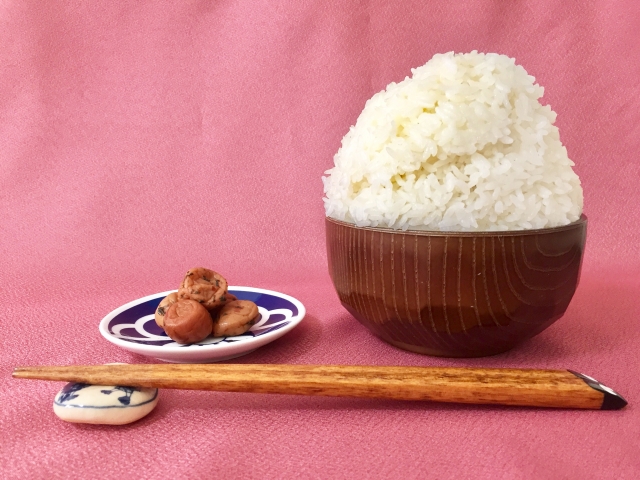A bowl of white rice served with umeboshi as a small salty-sour accent