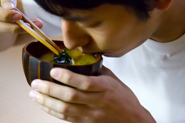 person eating miso soup made with dashi using chopsticks