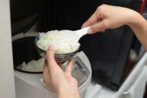Serving freshly cooked rice from a rice cooker into a bowl
