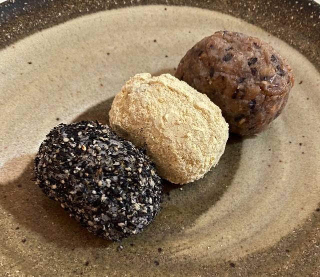 Three ohagi with different coatings, including kinako and black sesame, arranged on a ceramic plate