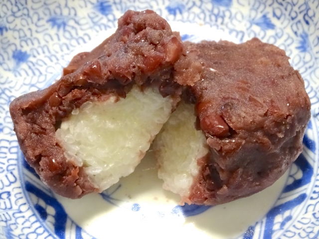 Cut anko ohagi showing sticky rice with visible grains inside the sweet red bean paste