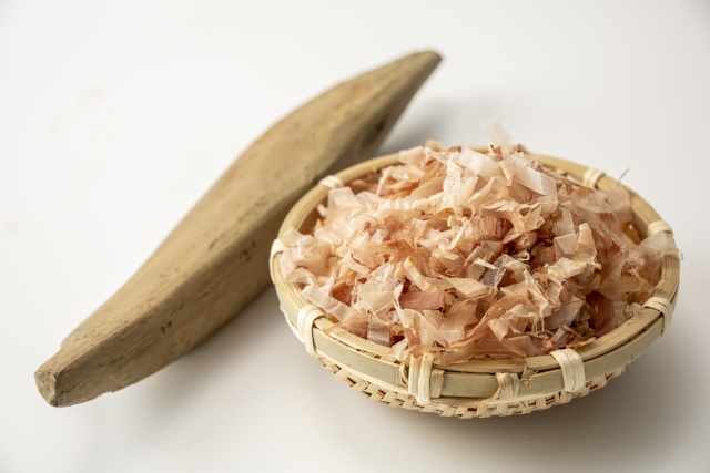 katsuobushi flakes in a bamboo basket with a traditional shaving tool