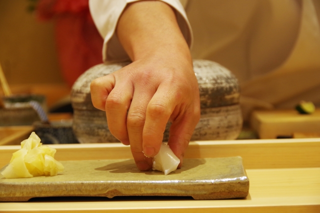 Sushi chef preparing nigiri with freshly grated wasabi