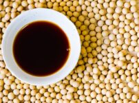 Tamari soy sauce in a small dish placed on soybeans