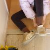 Person removing shoes at a Japanese genkan entryway before stepping inside