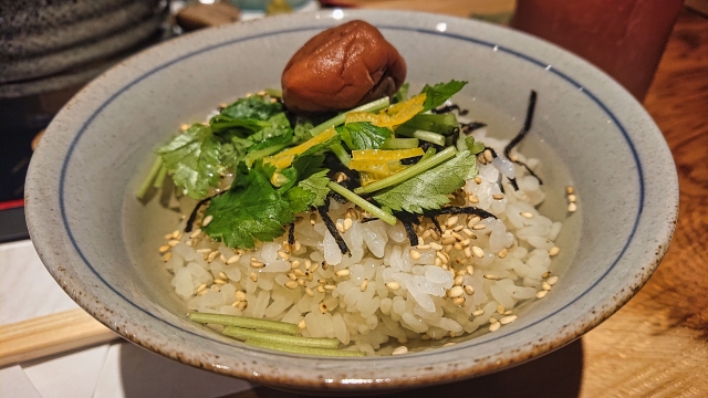 A bowl of ochazuke, rice topped with seasonings and served with tea or broth.
