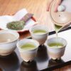 Gyokuro being poured into small Japanese teacups, with loose tea leaves and teaware arranged for a traditional tasting.