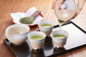 Gyokuro being poured into small Japanese teacups from a kyusu