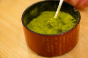 Fine konacha tea particles being scooped from a tea container.