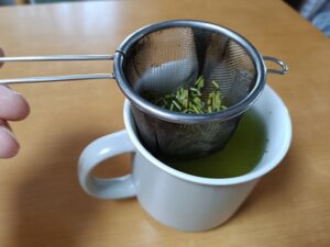 Japanese green tea brewed in a mug using a roomy metal tea strainer