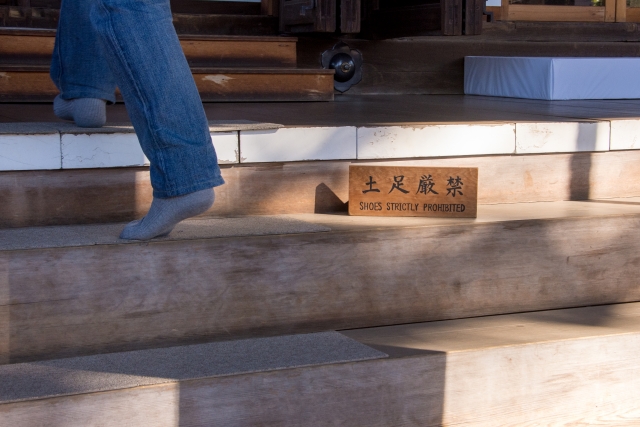 A sign reading “Shoes Strictly Prohibited” at the entrance of a Japanese building.