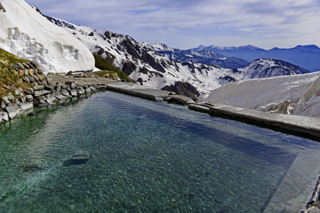 Outdoor onsen bath with clear water and sweeping views of snowy mountains