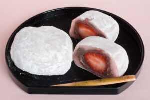 Ichigo daifuku cut open to show strawberry and sweet red bean paste inside a soft white outer layer