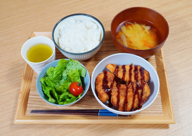 Japanese home meal with rice, miso soup, fried cutlet, and a cup of green tea