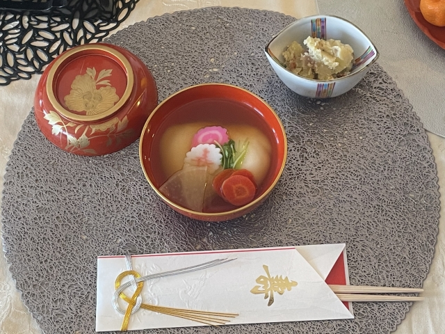 Japanese New Year table with ozoni soup, mochi, lacquerware, and celebratory chopsticks