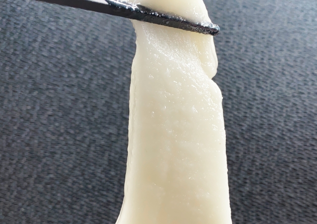 Traditional Japanese mochi stretching from chopsticks to show its soft, elastic texture