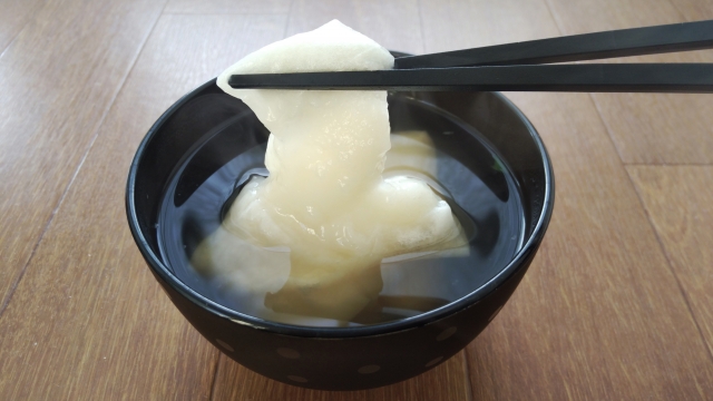 Cooked mochi stretching from a bowl to show its soft, elastic texture
