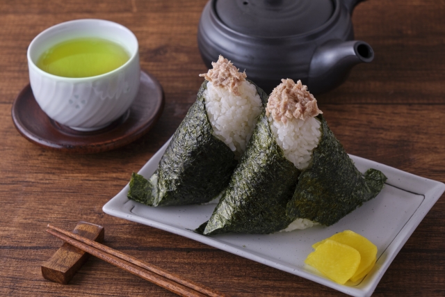 Japanese rice balls (onigiri) served with a cup of green tea and a kyusu teapot