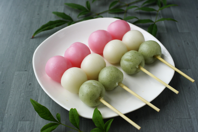 Colorful Japanese dango dumplings on skewers, including white, pink, and green varieties