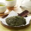 Sencha tea leaves with a Japanese teapot and cups of brewed green tea.