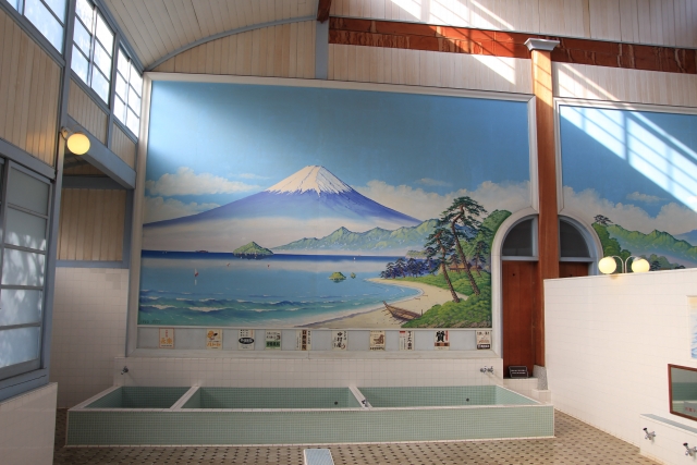 Japanese sento bathhouse interior with a large Mount Fuji mural above the tiled baths