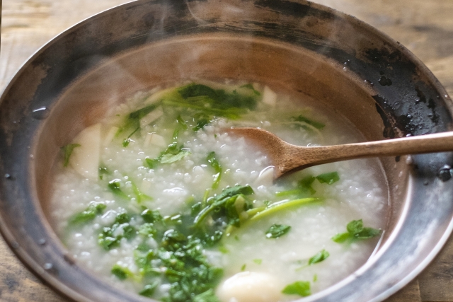 Nanakusa-gayu simmering in a pot, a gentle Japanese rice porridge cooked with seven spring herbs
