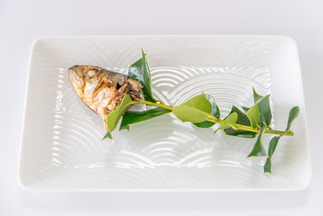 Hiiragi iwashi: grilled sardine head with holly leaves on a white plate