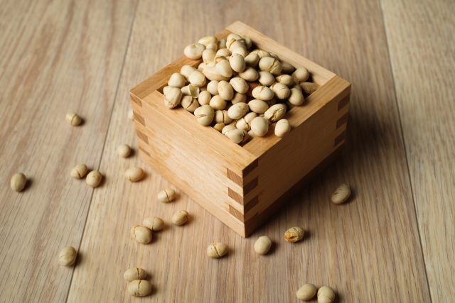 Roasted soybeans (fukumame) in a wooden masu box on a wooden floor