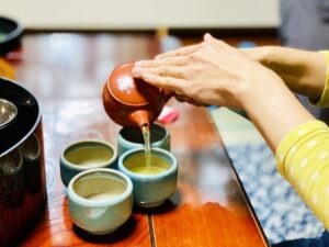 Pouring green tea into small cups in a traditional Japanese setting