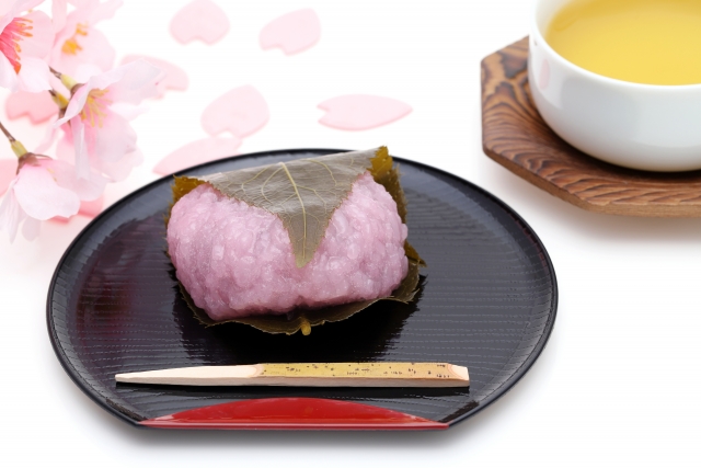 Sakura mochi served on a black plate with a cup of warm tea