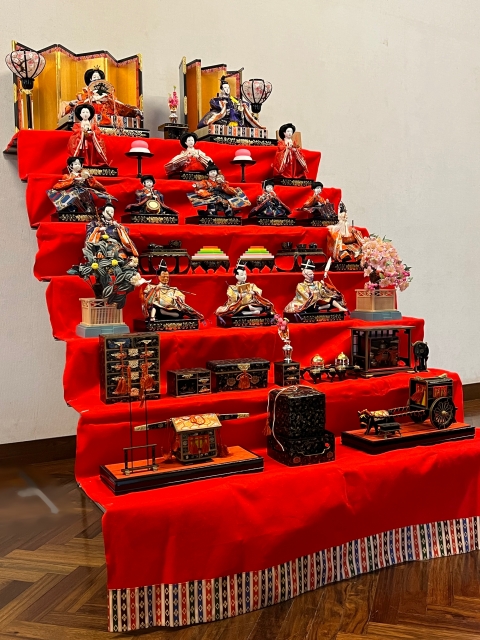 A full seven-tier hina doll display with court figures, furniture, and accessories arranged for Hinamatsuri