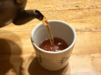 Hojicha being poured into a Japanese teacup, showing its warm amber-brown color