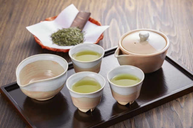A houhin teapot used for brewing gyokuro, served with small tea cups and loose tea leaves