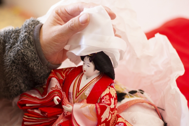 Carefully packing away hina dolls after Hinamatsuri to protect them from humidity and damage