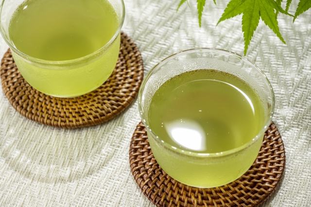 Freshly prepared cold sencha in small glass cups on woven coasters