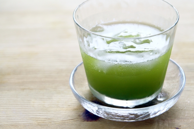 Cold green tea with a frothy surface served in a small glass
