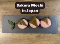 Sakura mochi arranged on a slate plate with the title “Sakura Mochi in Japan” overlaid