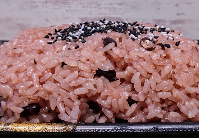 Sekihan topped with gomashio, highlighting the contrast between red rice and black sesame