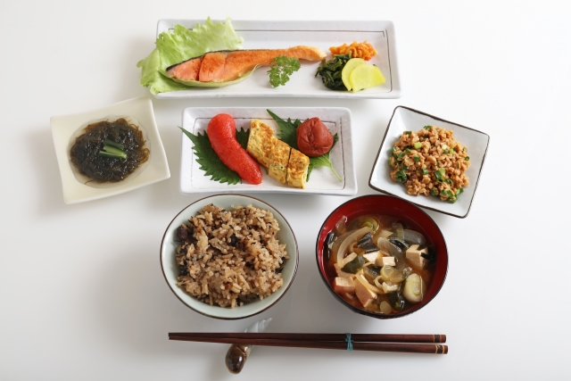 A Japanese meal featuring sekihan with miso soup, grilled salmon, and small side dishes served together on a dining table.