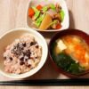 A traditional Japanese meal with sekihan, miso soup, and simmered vegetables served on a home dining table.