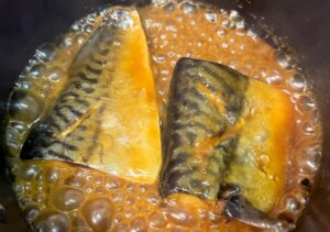 Japanese stir-fried eggplant coated in a rich miso-based sauce, served on a patterned white plate.