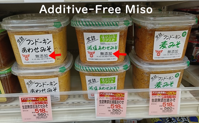 Japanese miso products labeled 無添加 (additive-free), with red arrows pointing to the kanji on supermarket packages.