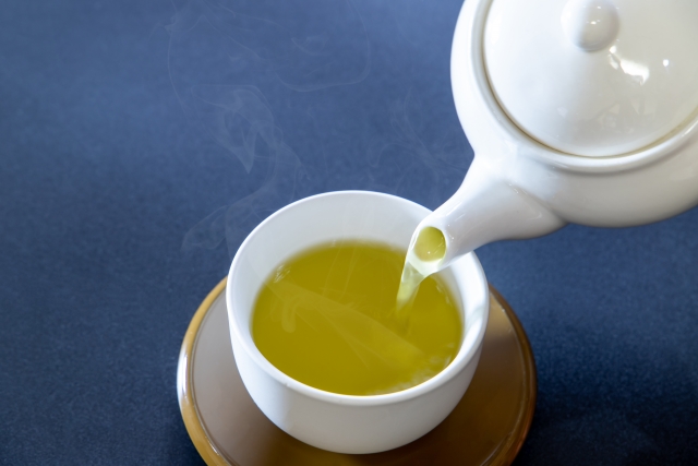 Japanese green tea being poured from a teapot into a teacup