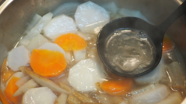 Daikon radish, carrots, and other vegetables simmering in broth before miso is added to Japanese miso soup.