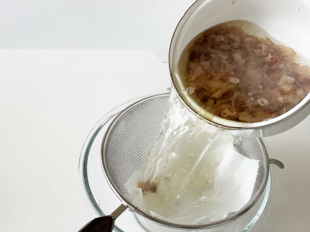 Straining freshly made dashi broth through a fine mesh strainer
